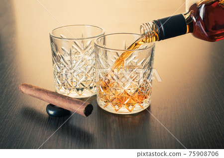 whiskey is poured into a glass from bottle whiskey is poured into a glass from bottle 75908706