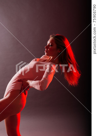 Slender female on a coloured background of neon color posing in a bodysuit 75908790