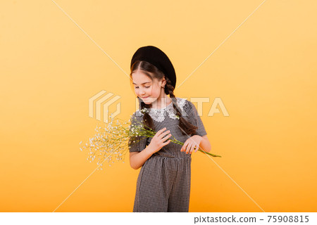 Funny child girl smiling with bouquet of flowers on a coloured background 75908815