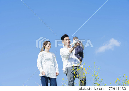 Parents holding their baby high under the blue sky Parents holding their baby high under the blue sky 75911480