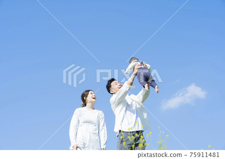 Parents holding their baby high under the blue sky 75911481