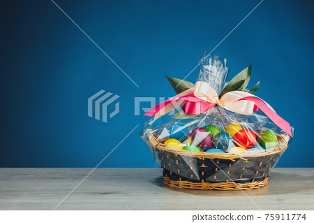 Easter gift basket with multicolor eggs, blue background Easter gift basket with multicolor eggs, blue background 75911774