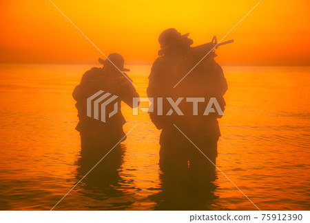 Commando soldiers walking in water and aiming gun 75912390
