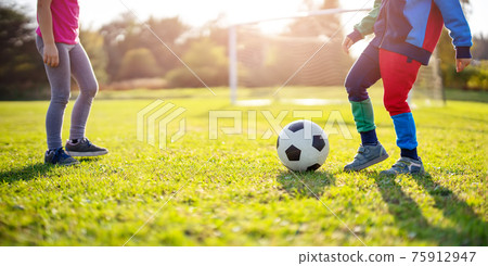 Children playing football on the field with gates. 75912947