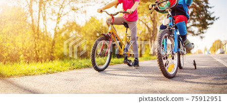 Cute children riding on bicycles on asphalt road in summer. 75912951