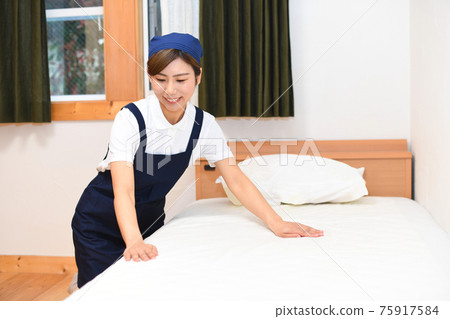 A woman who is a housekeeper who makes a bed 75917584