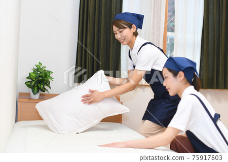 Housekeeper women doing bed-making 75917803