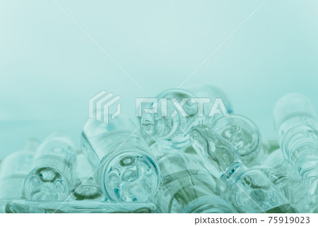 Glass medical ampoule vial for injection. Medicine is liquid sodium chloride with of aqueous solution in ampulla. Close up. Bottles ampule multicolor. 75919023