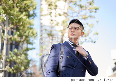 Asian businessman tightening up outside Asian businessman tightening up outside 75919648