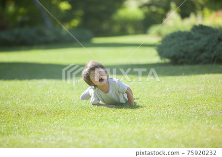 A child who falls on the grass and cries 75920232