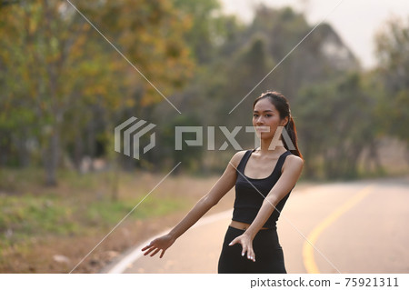 Healthy young asian woman in sportswear exercises outdoors in the evening. 75921311