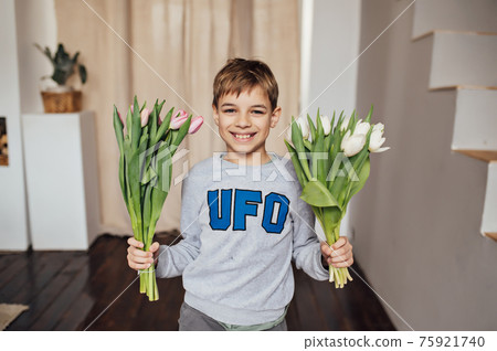 The boy smiles fervently with a bouquet of flowers The boy smiles fervently with a bouquet of flowers 75921740