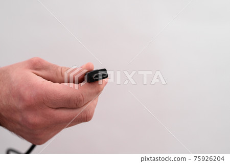 HDMI cable in hand, for transmitting audio and video signal.  75926204