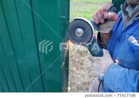 Cutting of a metal fence by means of the grinding corner car, installation of a fence and construction works. Cutting of a metal fence by means of the grinding corner car, installation of a fence and construction works. 75927586
