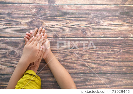 close up of child hand holding senior women's hand  75929445