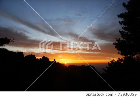 Huangshan Mountain in Anhui Province, China. Sunset over Huangshan with colorful sky and clouds, a silhouette of the mountain and foreground tree. Sunset near the summit of Huangshan Mountain, China. Huangshan Mountain in Anhui Province, China. Sunset over Huangshan with colorful sky and clouds, a silhouette of the mountain and foreground tree. Sunset near the summit of Huangshan Mountain, China. 75930359