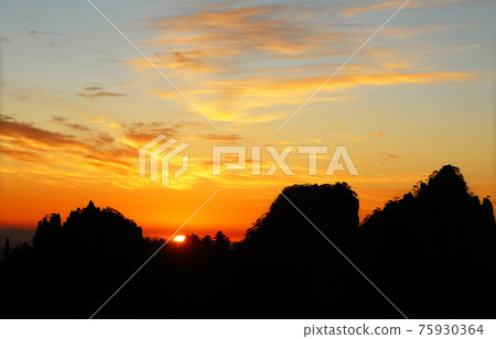 Huangshan Mountain in Anhui Province, China. Sunrise over Huangshan with a colorful sky, clouds and a silhouette of trees on the mountain. Sunrise near the summit of Huangshan Mountain, China. Huangshan Mountain in Anhui Province, China. Sunrise over Huangshan with a colorful sky, clouds and a silhouette of trees on the mountain. Sunrise near the summit of Huangshan Mountain, China. 75930364