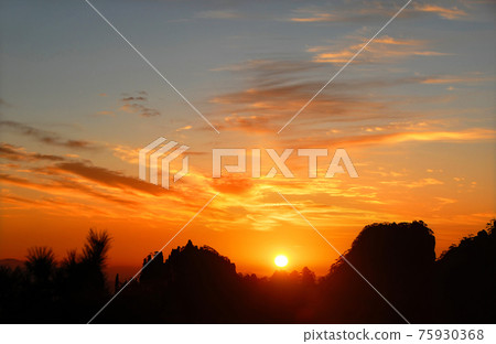 Huangshan Mountain in Anhui Province, China. Sunrise over Huangshan with colorful sky and clouds. Horizon in focus. Foreground trees not in focus. Sunrise near the summit of Huangshan Mountain, China. Huangshan Mountain in Anhui Province, China. Sunrise over Huangshan with colorful sky and clouds. Horizon in focus. Foreground trees not in focus. Sunrise near the summit of Huangshan Mountain, China. 75930368