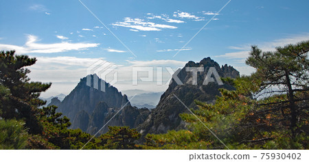 Huangshan Mountain in Anhui Province, China. View of Lotus Peak on right and Celestial Capital Peak on left from Bright Top. Scenic view of the highest peaks and trees on Huangshan Mountain, China. Huangshan Mountain in Anhui Province, China. View of Lotus Peak on right and Celestial Capital Peak on left from Bright Top. Scenic view of the highest peaks and trees on Huangshan Mountain, China. 75930402