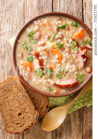 Slovenian barley and bean soup with smoked meat close-up in a bowl. vertical top view Slovenian barley and bean soup with smoked meat close-up in a bowl. vertical top view 75931795