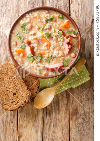 Ricet barley and bean soup with smoked meat and vegetables close-up in a bowl. vertical top view Ricet barley and bean soup with smoked meat and vegetables close-up in a bowl. vertical top view 75931796