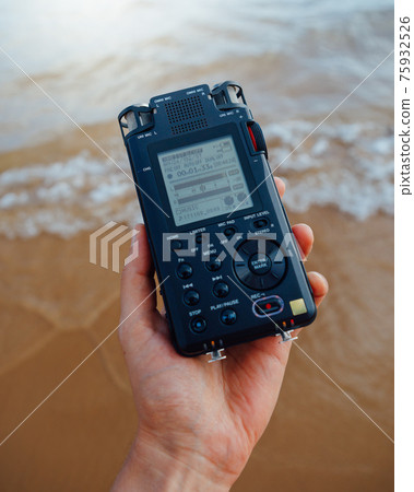 portable audio recorder in hand recording ambient sounds of sea portable audio recorder in hand recording ambient sounds of sea 75932526