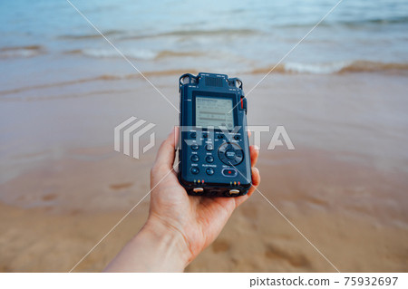 portable audio recorder in hand recording ambient sounds of sea 75932697