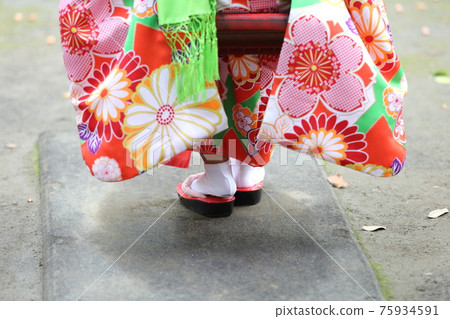 A close-up of a girl's feet wearing a red kimono and sandals for Shichi-Go-San (a traditional Japanese rite of passage for children). A close-up of a girl's feet wearing a red kimono and sandals for Shichi-Go-San (a traditional Japanese rite of passage for children). 75934591