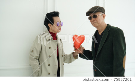 Asian elder senior couple hold love red balloon in fashion winter clothes happy marriage life 75937201
