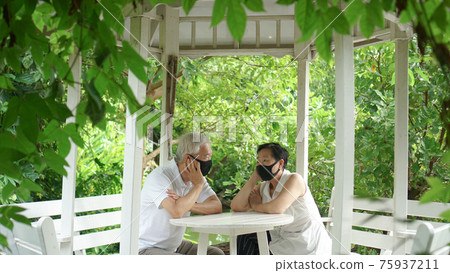 Asian elder senior couple wear mask quarantine eascape in green natural park background happy in nature Asian elder senior couple wear mask quarantine eascape in green natural park background happy in nature 75937211