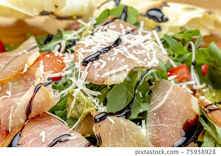 Fresh salad with tomatoes, arugula and bacon, sprinkled with parmesan cheese. Fresh salad with tomatoes, arugula and bacon, sprinkled with parmesan cheese. 75938928