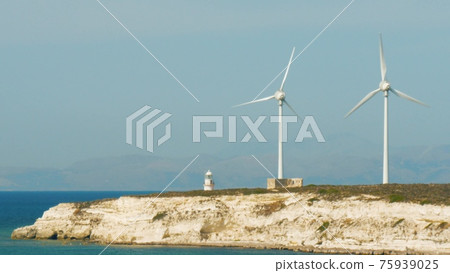 Wind turbines with blades in field vith blue sky. Alternative electric energy production. 75939025