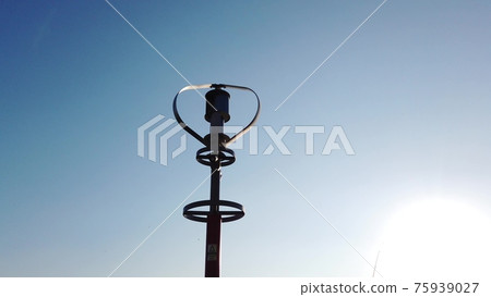 Vertical axis wind turbine utilize renewable wind energy while spinning against blue sky. 75939027