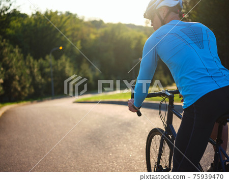 Keep healthy. Rear view of male cyclist on the road. Biker riding a bike in park on a sunny day Keep healthy. Rear view of male cyclist on the road. Biker riding a bike in park on a sunny day 75939470
