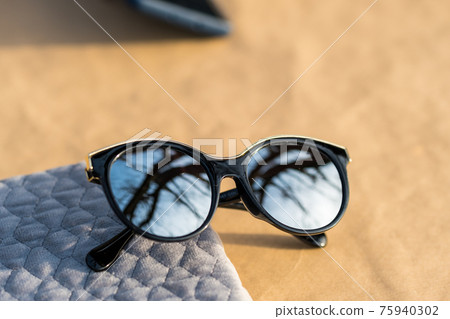 Fashion cat eye sunglasses model for ladies with big round silver lenses and black frame shoot outside in a sunny day closeup. Selective focus Fashion cat eye sunglasses model for ladies with big round silver lenses and black frame shoot outside in a sunny day closeup. Selective focus 75940302