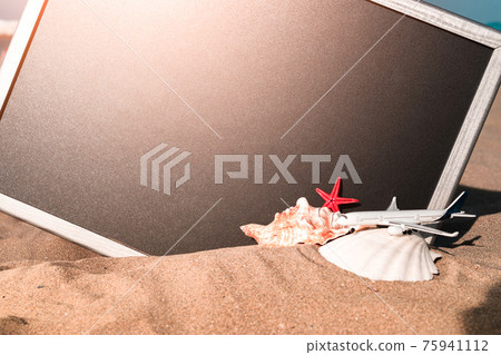 Sea shells. Starfish, seashells, toy plane and globe near blackboard on ocean nature beach. Tranquil beach scene with copy space. Sea shells. Starfish, seashells, toy plane and globe near blackboard on ocean nature beach. Tranquil beach scene with copy space. 75941112