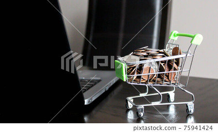 Shopping cart full of money and laptop on a wooden desktop: e-commerce, e-payments and online shopping concept 75941424