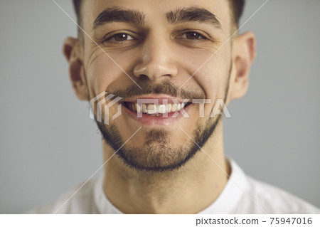Closeup studio portrait of a happy young Caucasian man with a friendly open smile Closeup studio portrait of a happy young Caucasian man with a friendly open smile 75947016