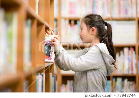 Girl choosing a book in the library 75948744