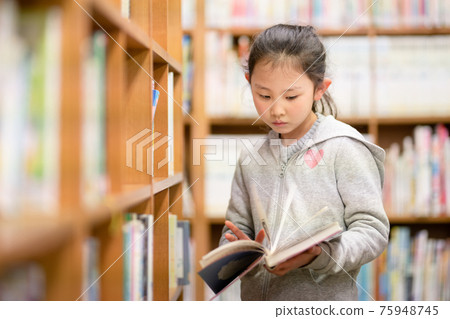 Girl choosing a book in the library 75948745