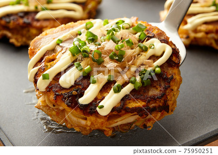 Small size okonomiyaki made on a hot plate 75950251