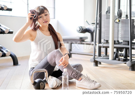 Asian woman taking a break in the training gym Asian woman taking a break in the training gym 75950720
