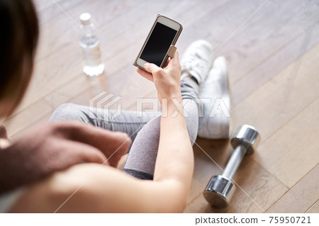 亞洲女性在智能手機上觀看訓練應用 75950721