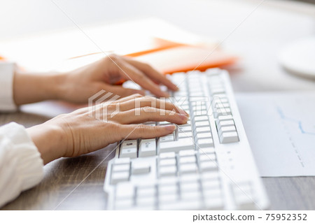 Female hand operating a computer keyboard Female hand operating a computer keyboard 75952352
