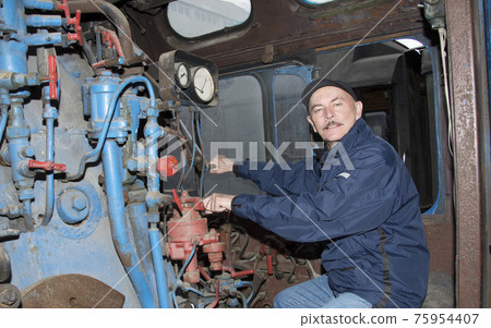 The machinist operates a steam locomotive The machinist operates a steam locomotive 75954407