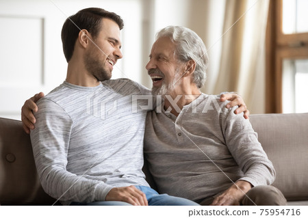Smiling old dad and adult son relax at home Smiling old dad and adult son relax at home 75954716