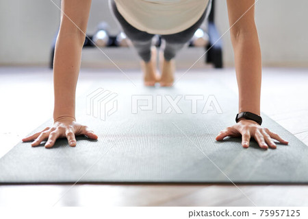 Asian woman doing push-ups in a training gym Asian woman doing push-ups in a training gym 75957125