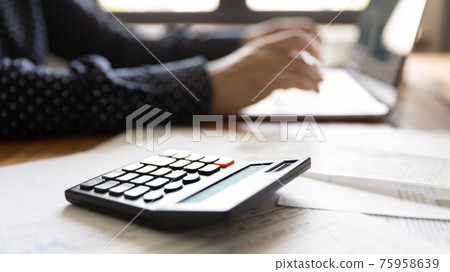 Close up woman using laptop, calculating bills, checking financial documents 75958639