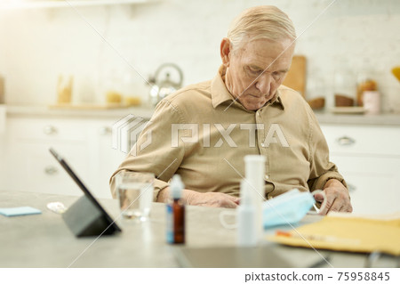 Concerned aged man touching his stomach while at home Concerned aged man touching his stomach while at home 75958845
