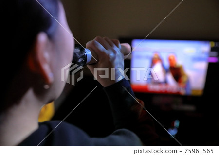 A woman who enjoys singing karaoke enthusiastically 75961565